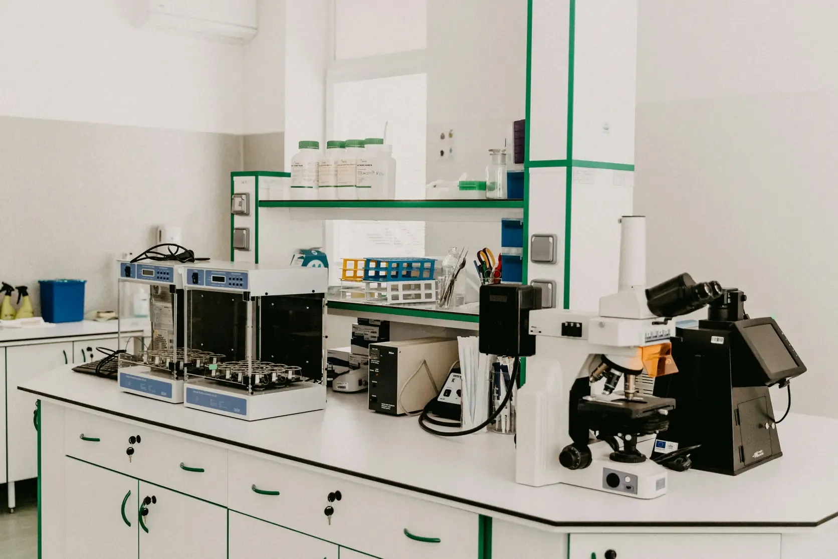 A laboratory bench with two incubators, a microscope and a rack of prepared tubes.