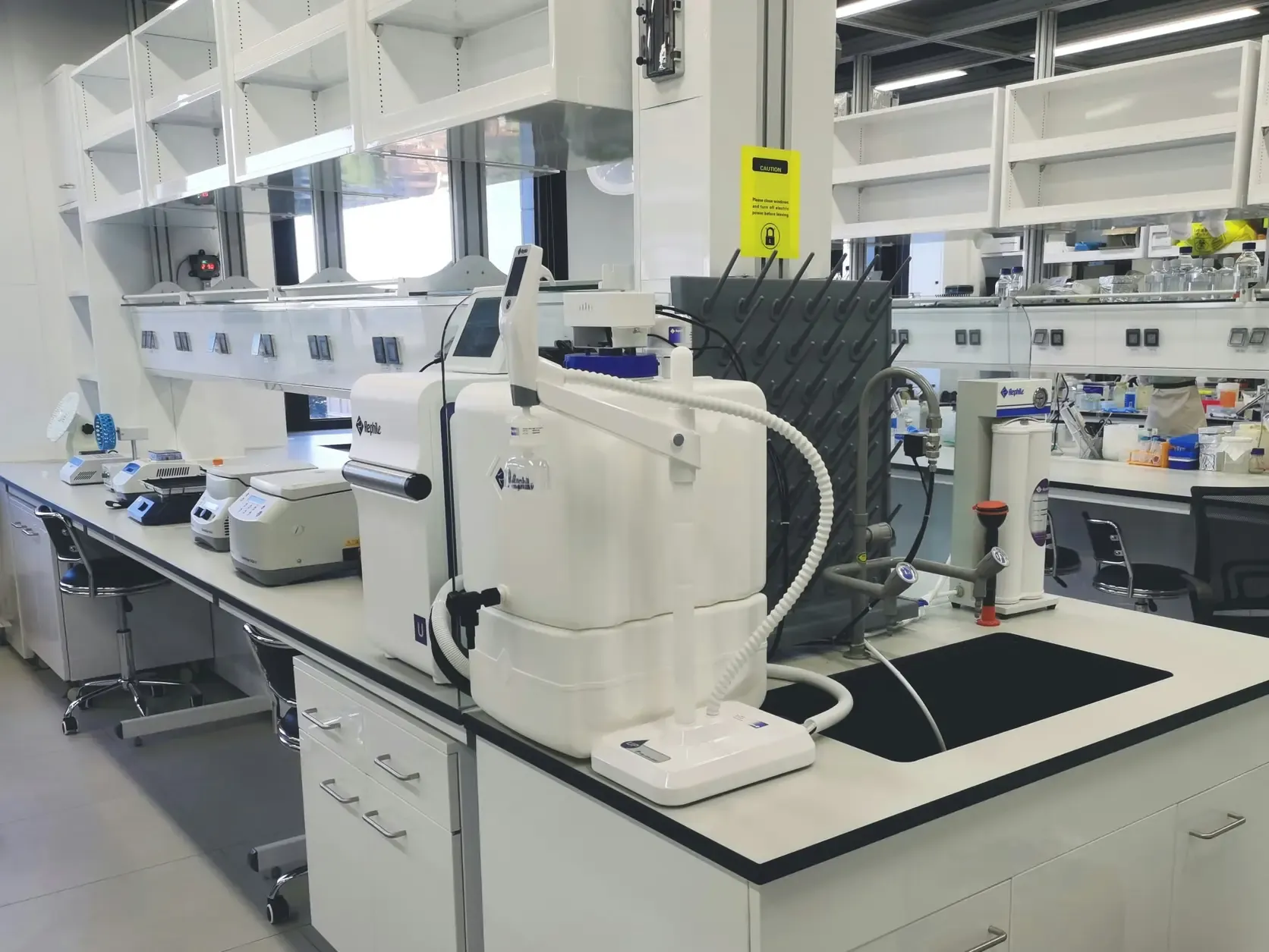 A laboratory bench running the length of a room, with instruments and glassware along it.