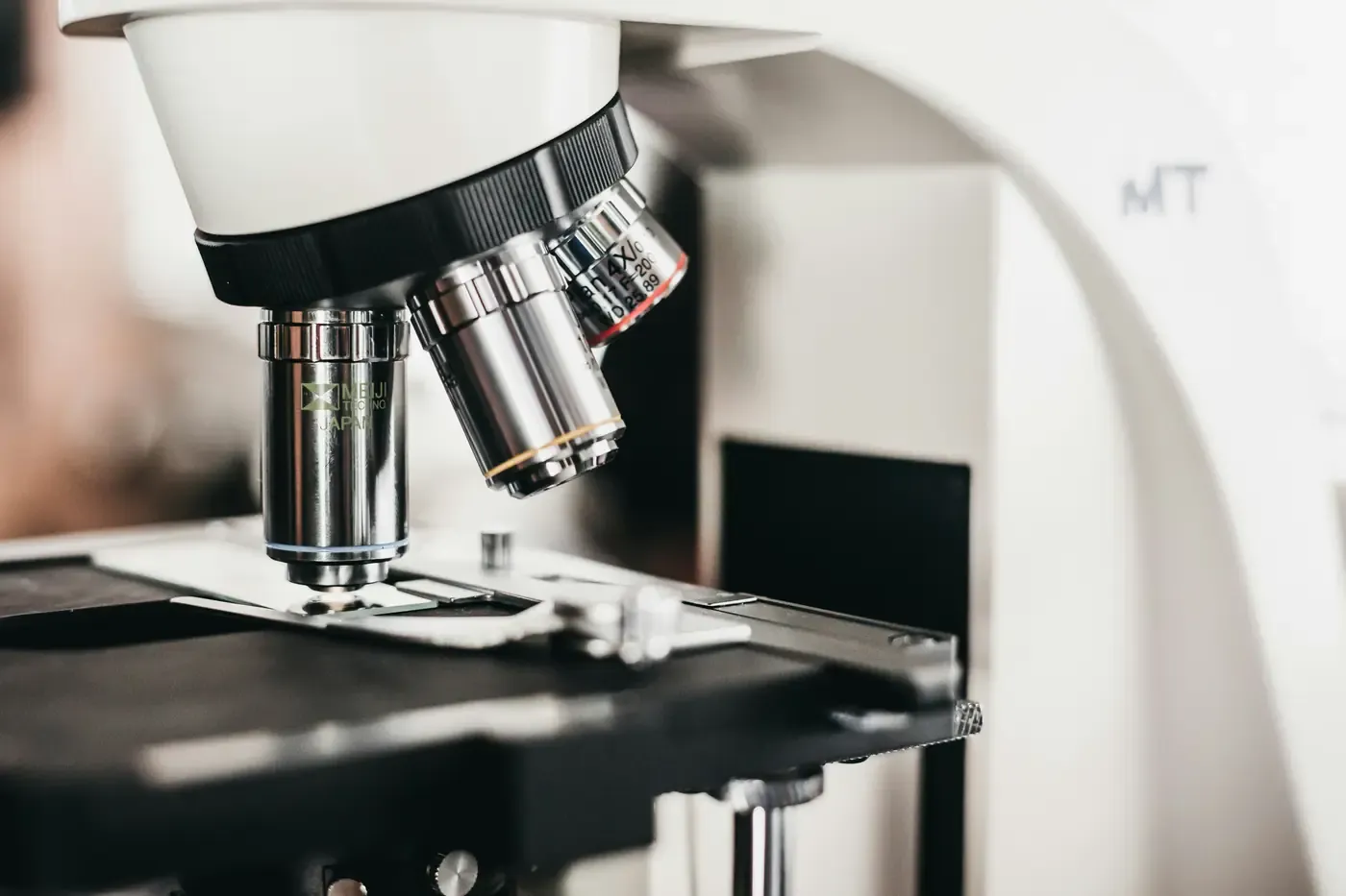The objective lenses of a laboratory microscope, close, above a prepared slide.
