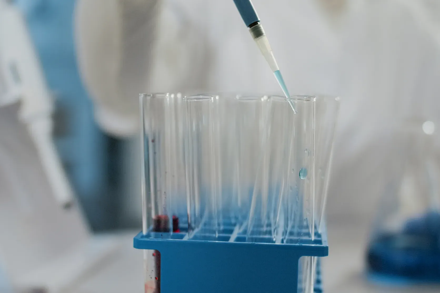 A pipette delivering liquid into a rack of glass test tubes.