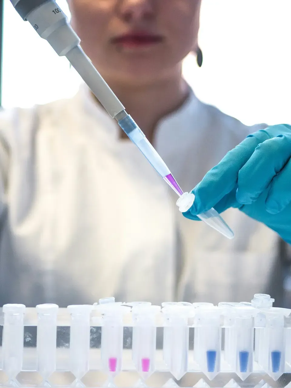 An analyst pipetting a sample into a microtube, a rack of labelled tubes in front of them.